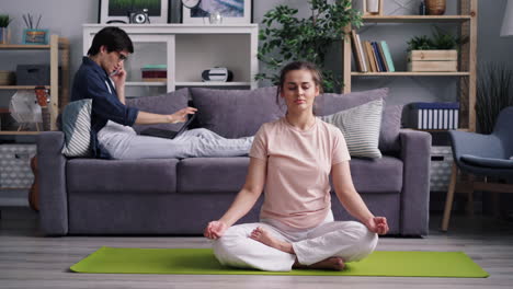 woman meditating at home while partner works