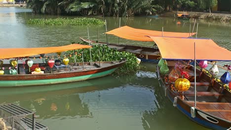 parked tour boats wait to take tourists and visitors on an evening tour of the scenic thu bon river in the old quarter of hoi an, vietnam.