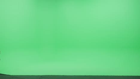 green screen chroma key studio: beautiful blonde woman wearing stylish coat walks across room right to left. side view camera shot