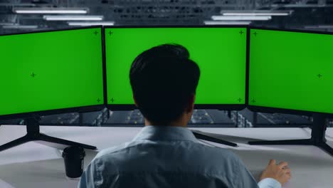 데이터 센터에서 여러 컴퓨터 모니터를 모방하는 동안 스트레칭하는 피곤한 아시아 남자의 뒷면