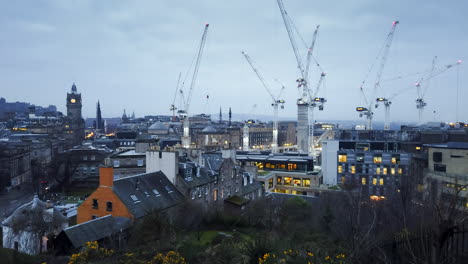 Timelapse-Temprano-En-La-Mañana-De-Edimburgo-Cuando-Amanece-Sobre-La-Ciudad,-Mostrando-Grandes-Grúas-De-Construcción-Trabajando-Y-El-Tráfico-Abriéndose-Paso-Por-Las-Calles