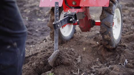 hombre preparando el suelo del jardín con un cultivador, nueva temporada de siembra en una granja de verduras caseras orgánicas. filmado en cámara lenta