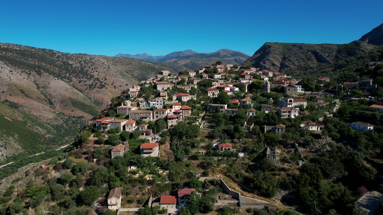 Panoramaby på en klippig kulle: Stenhus i medelhavsstil som reser sig över klippor i Albanien.