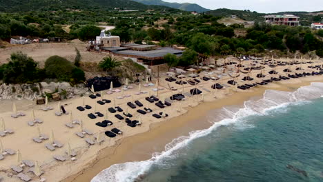 High-angle-aerial-view-of-blue-waves-crashing-in-over-golden-beach-at-luxury-resort