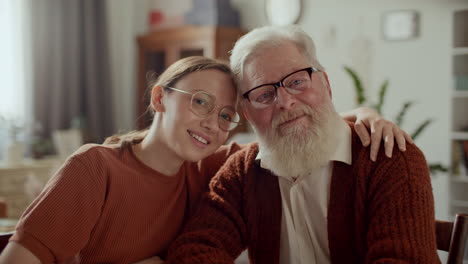 portrait of happy woman hugging elderly grandfather at home
