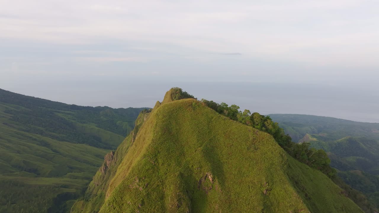 Hutan lebat membingkai gunung berapi aktif saat matahari terbit, Flores, Indonesia