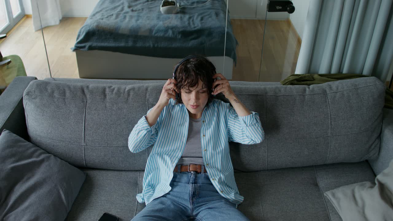 Woman Relaxing on Sofa Listening to Music