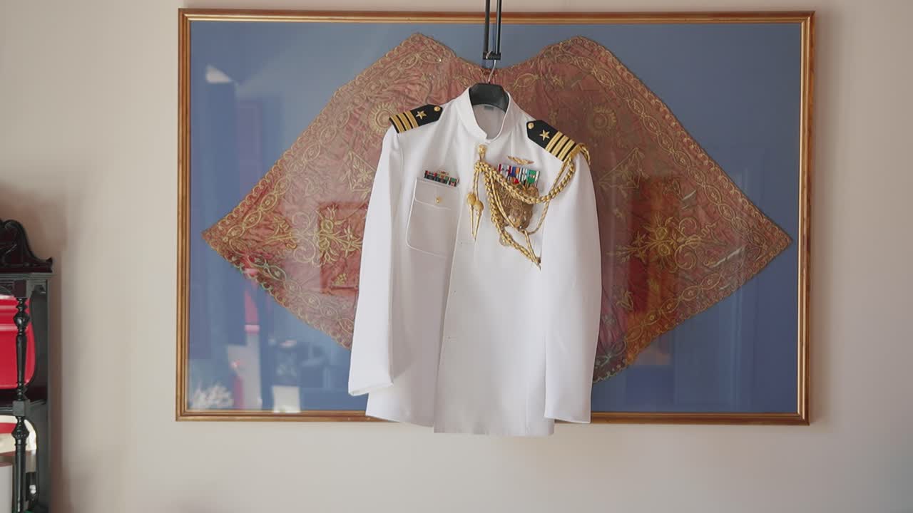 Traje de gala azul marino colgando en un marco, simbolizando honor y tradición.