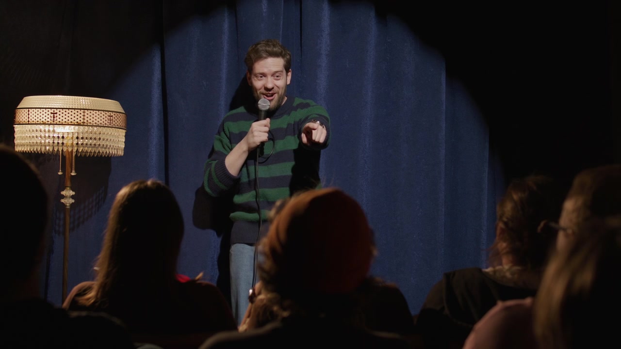 Comico stand-up che parla al pubblico durante uno spettacolo in un comedy club