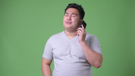 초록색 배경에 젊은 잘생긴 과체중 아시아인