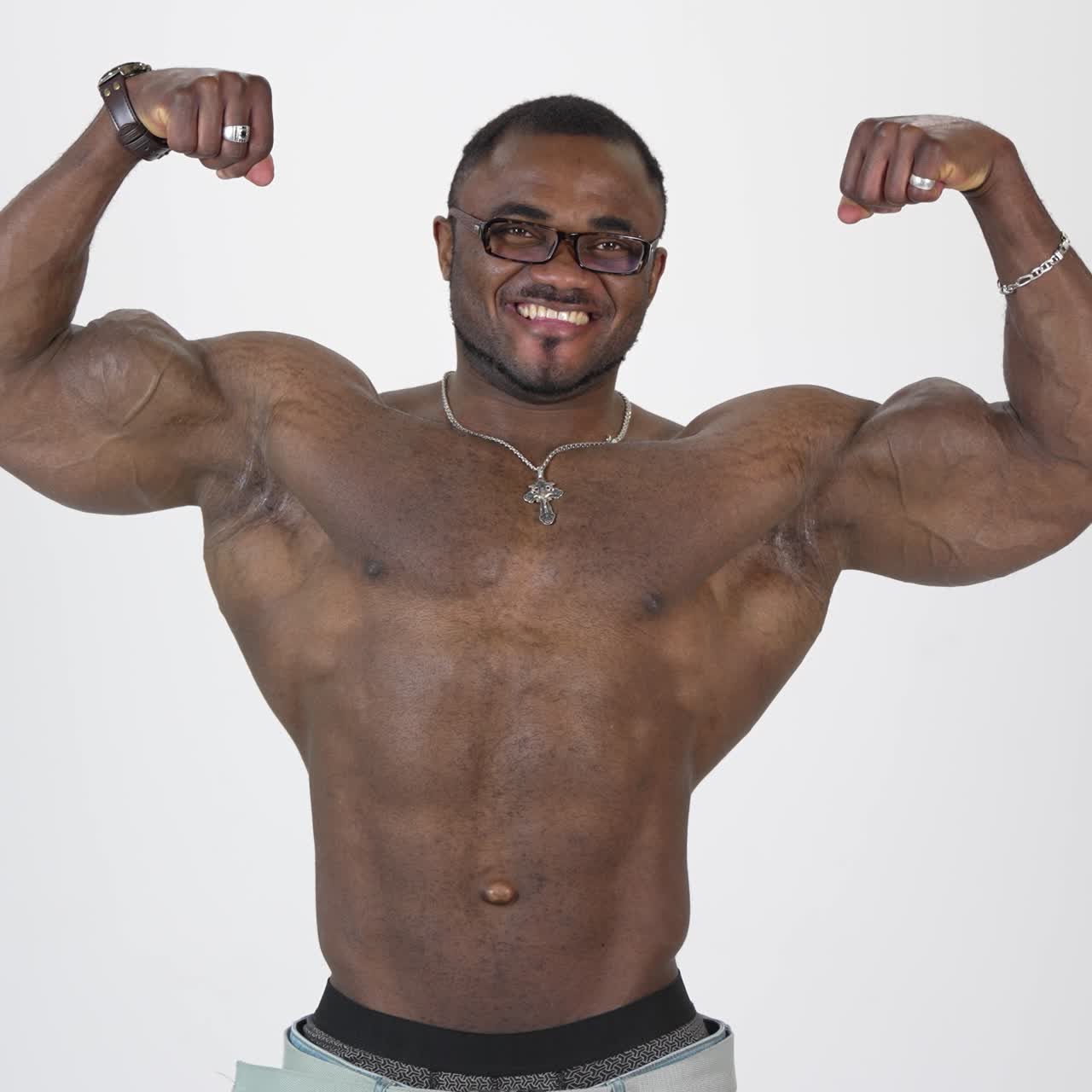 Athletic black man posing on camera. Portrait of a smiling african american guy without shirt showing his muscles and looking on camera on white background