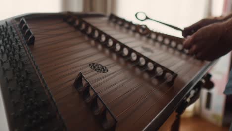 instrumento musical de cuerda de dulcimer tradicional de madera martillado, primer plano mano caucásica tocar suavemente música clásica