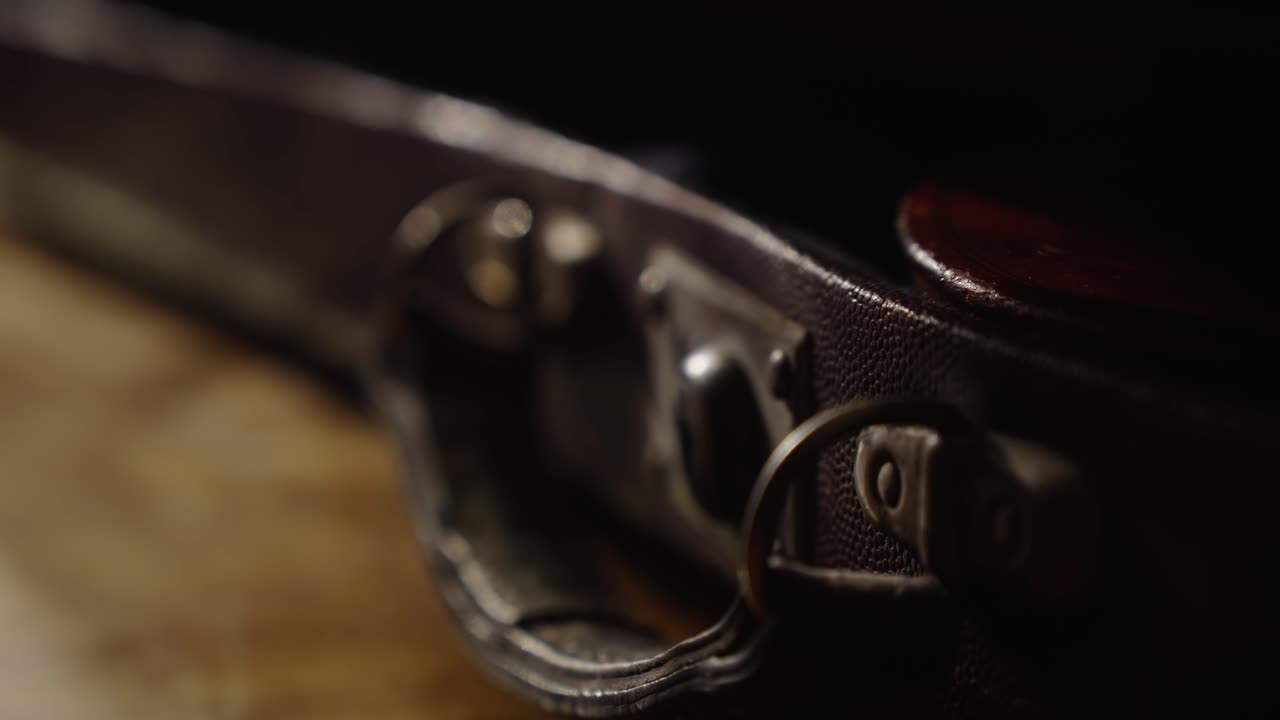 Musician opens lock on worn antique violin case Close-up focus
