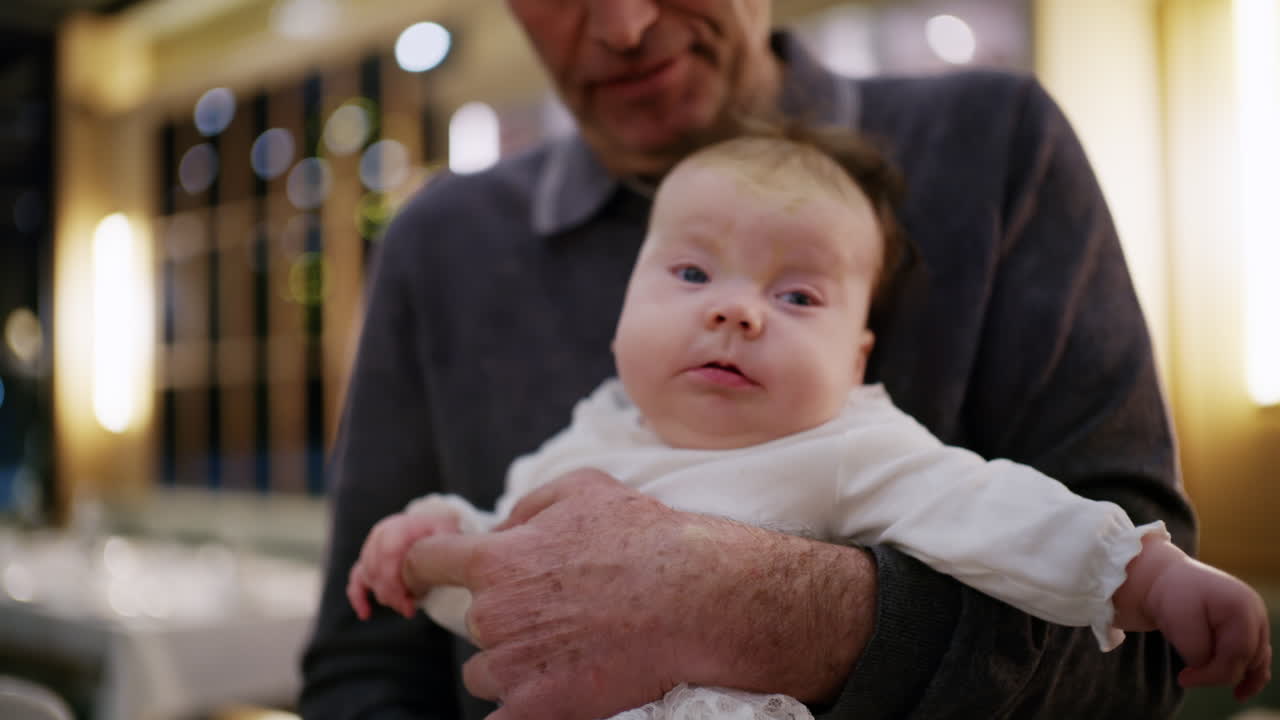 Sıcak ışıklı bir restoranın iç mekanında bebek tutan orta yaşlı bir adam