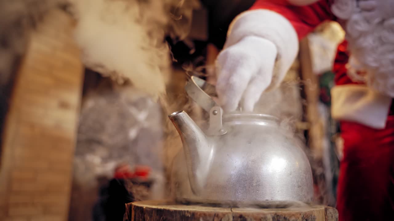 Metal kettle boiling with white steam. Santa removing the cover of the kettle with hot water indoors. Close-up. Christmas time.