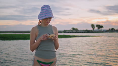 river girl holding fish in hands at beautiful evening sky. smiling traveler rest