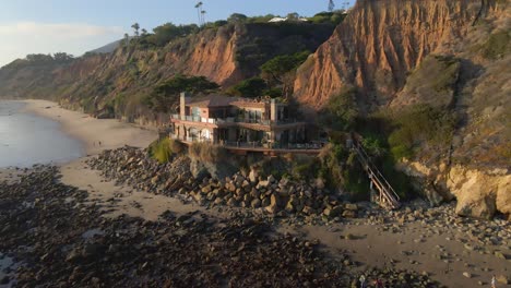 casa de super lujo con vista aérea frente al océano, propiedades inmobiliarias caras frente al océano en el parque estatal de la playa el matador en malibu california durante la hora dorada, alquileres de vacaciones