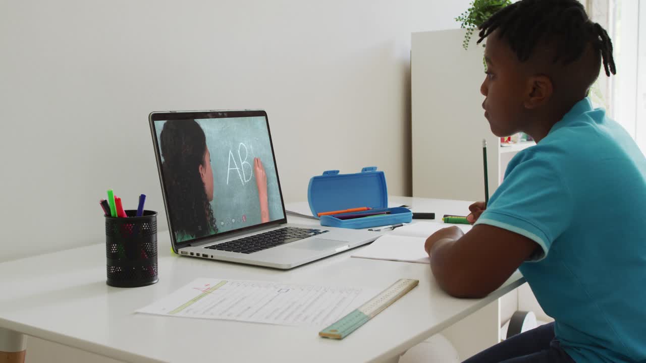 African american boy sitting at desk using laptop having online school lesson