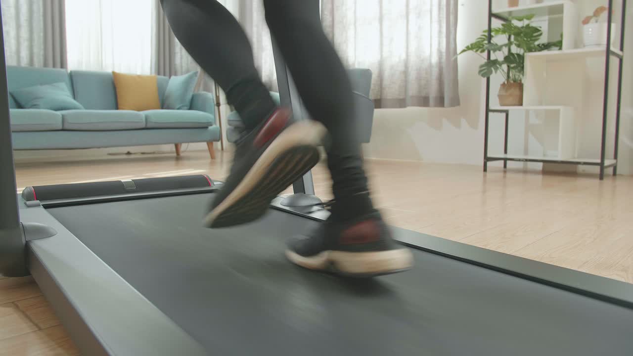 Back View Legs Of Asian Woman Running On A Treadmill At Home