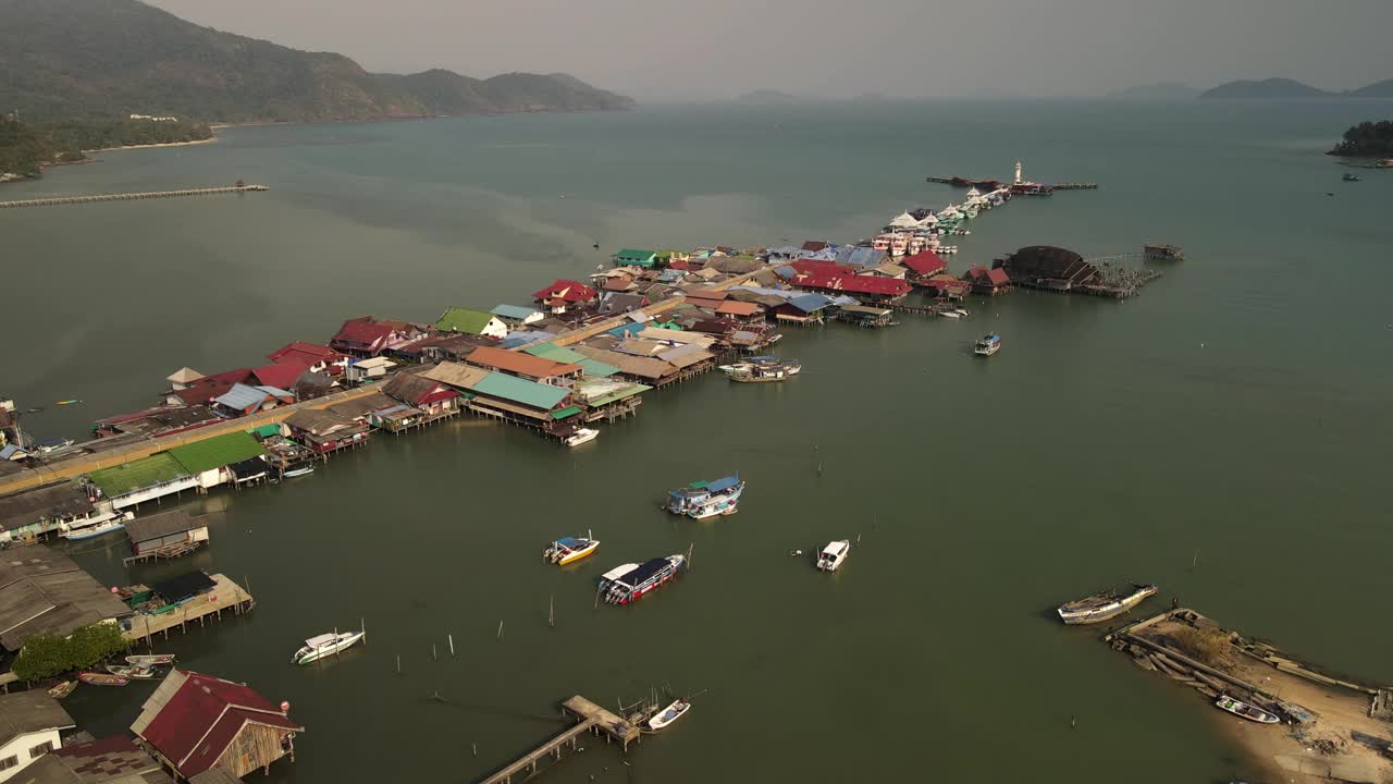 Rising aerial tilt high above the boats and structures on the Bang Bao fishing pier in Koh Chang, Thailand.