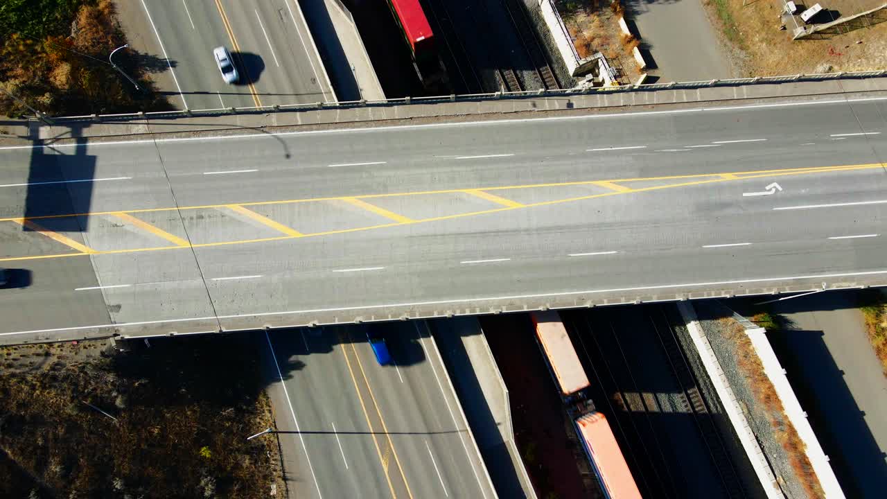 vista de pájaro de velocidad normal tiro de drones estáticos del puente de la autopista 1 y la autopista de cabeza amarilla en kamloops bc canadá con trenes y vehículos moviéndose por las calles en un día soleado