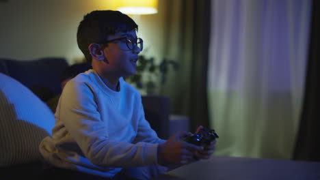 two young boys at home having fun playing with computer games console on tv fighting over controllers late at night 4