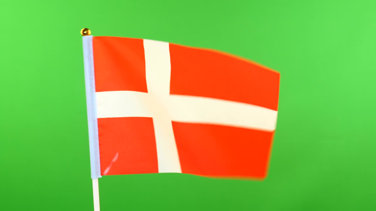 덴마크 발은 발 기둥 위에 초록색 배경으로 바람에 흔들리고 있습니다.