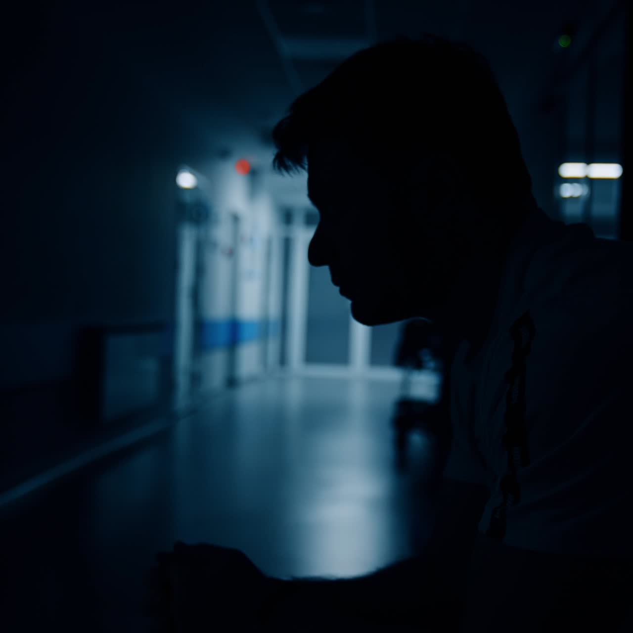 Uomo nervoso si sfrega le mani e il viso mentre aspetta nel corridoio dell'ospedale. Marito preoccupato aspetta nel corridoio durante il travaglio. Vista laterale