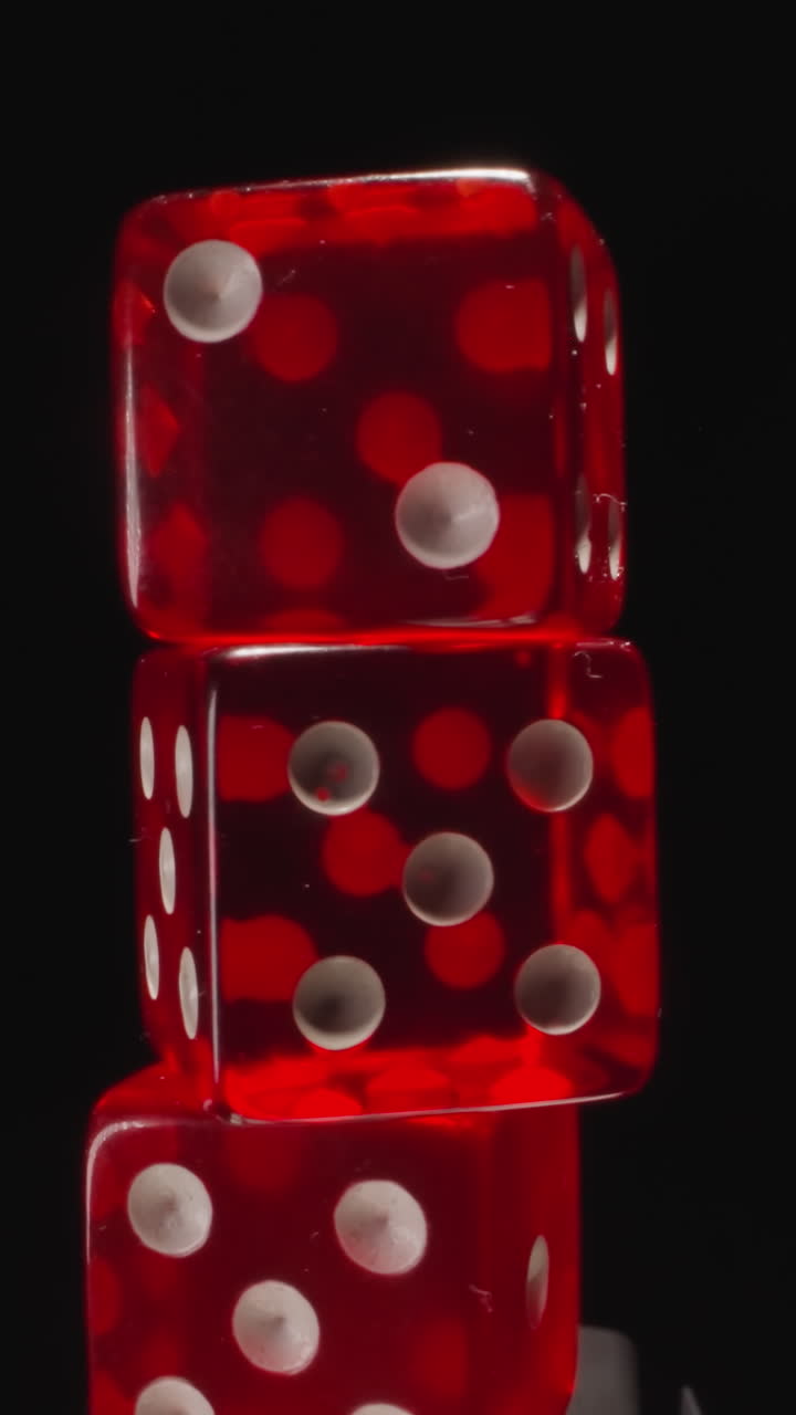 Stack of small transparent red cubes with white spots spins on black background. Dices with dots designed for fun gambling games and entertainment macro