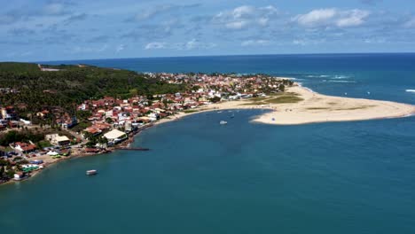 Dolly-out-aerial-drone-wide-shot-of-the-tropical-beach-town-of-Barra-do-Cunhaú-in-Canguaretama-where-the-large-Curimataú-river-meets-the-sea-in-the-state-of-Rio-Grande-do-Norte,-Brazil