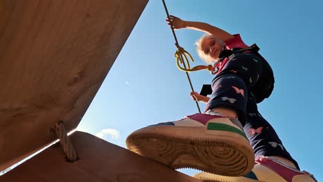 niña feliz jugando en la atracción de tarzán en el patio de recreo en el parque de atracciones