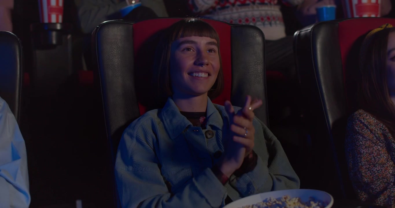 Junge Frau klatscht beim Ansehen eines Films im Kino