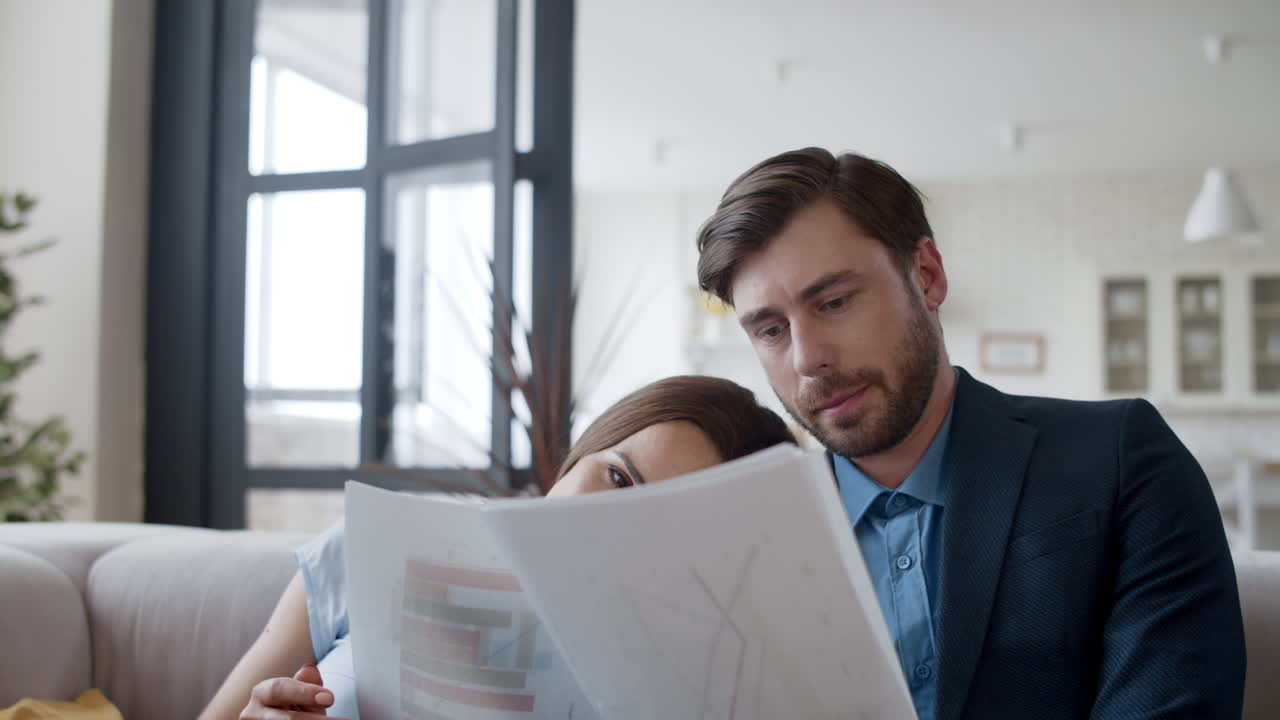 Business couple working with papers on couch in home office.
