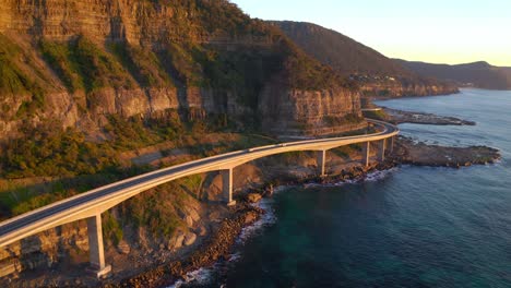 puesta de sol en el puente del acantilado marino con vehículos que viajan cerca de wollongong al sur de sydney, nueva gales del sur, australia