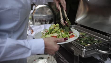 Slow-motion-shot-of-a-woman-filling-her-plate-up-with-a-freshly-prepared-salad
