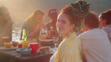 portrait of young woman with dreadlocks at lake party with friends