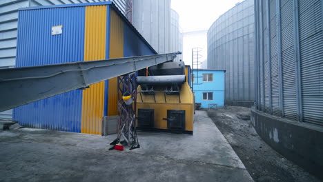 exterior of the elevator furnace premises with a long orthogonal tube. view of the exterior with gradual distancing. huge tanks at the backdrop.