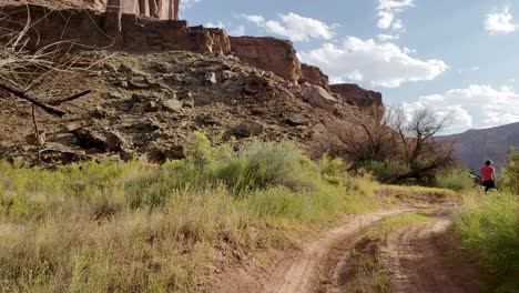 Following-guy-walking-on-trail-near-canyon-in-Utah