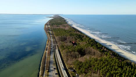 toma panorámica aérea de hel con bosque, tráfico en carretera, playa de arena y olas de mar báltico azul en verano - polonia, europa