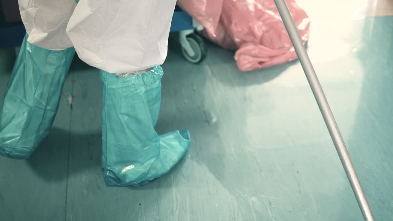 Cropped Image Of A Hospital Cleaner Mopping The Floor With A Microfiber Mop - Wearing PPE For Covid-19 Protection - high angle shot