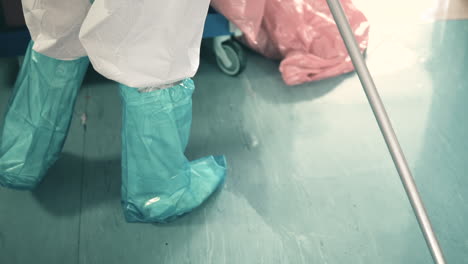 cropped image of a hospital cleaner mopping the floor with a microfiber mop - wearing ppe for covid-19 protection - high angle shot