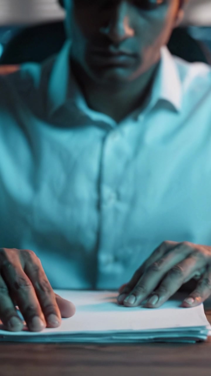 A focused individual examines important documents with concentration, surrounded by an atmospheric ambiance that highlights the significance of the task at hand.