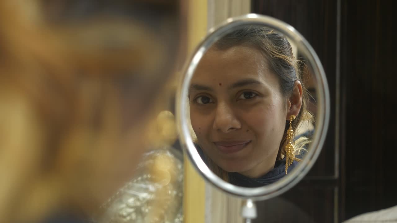 Young beautiful asian woman looking at mirror with 18k HUID certified gold earrings