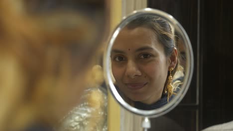 young beautiful asian woman looking at mirror with 18k huid certified gold earrings