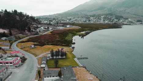 Aerial-Flying-Over-Avenue-Enrique-Garces-Beside-Lake-San-Pablo-At-Foothills-Of-Imbabura-Volcano