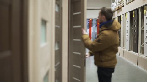 Man-in-hardware-store-choosing-a-door-checking-a-lock