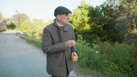 man smells freshly picked mandarins while walking down the street