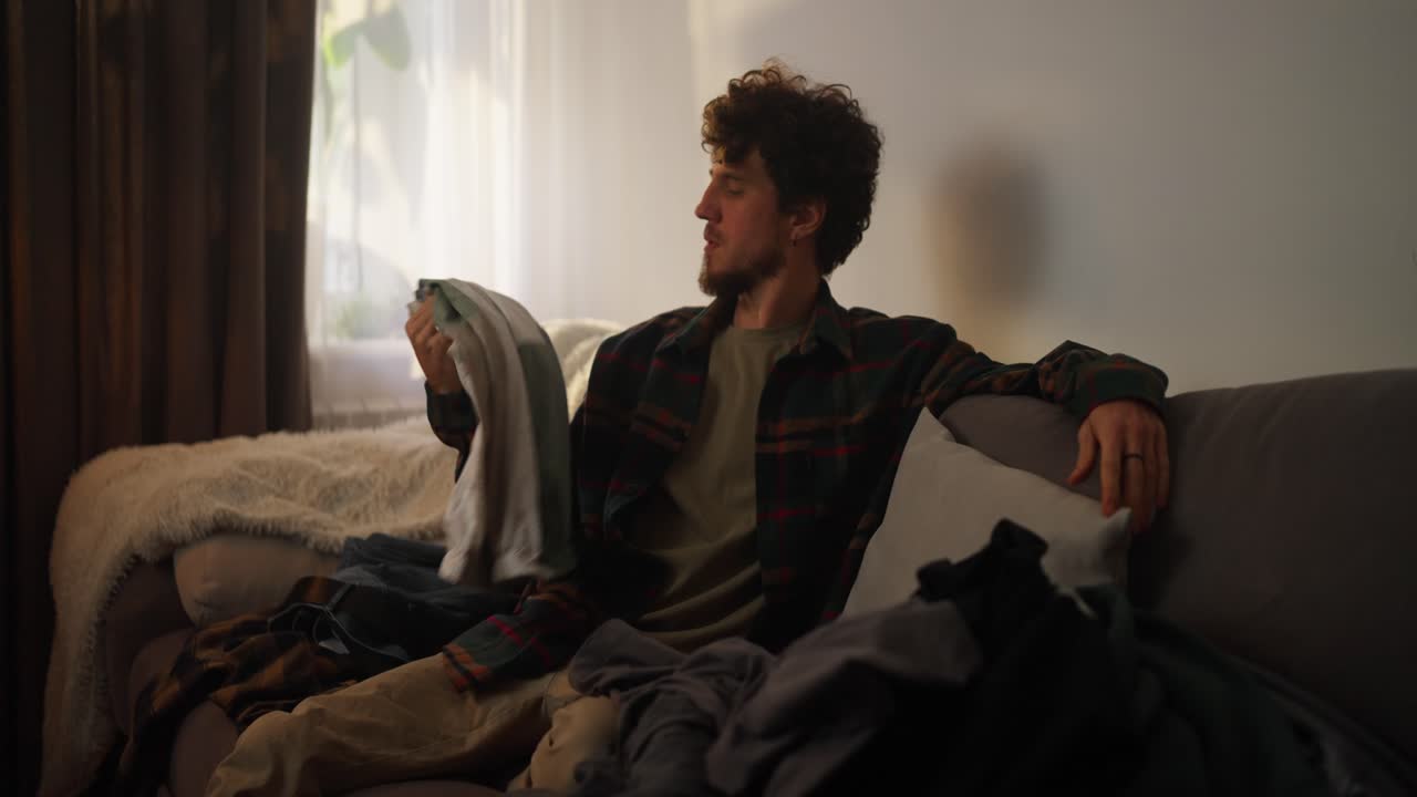 소파 에 옷 을 놓고 있는 사람