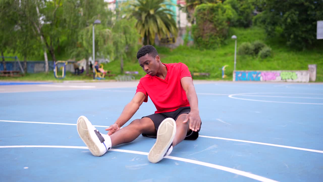 Young man stretching and preparing on an outdoor sports court
