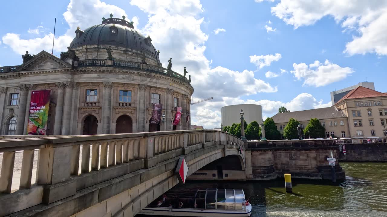 Tour boat cruises past historic domed museum on Spree River in vibrant Berlin cityscape
